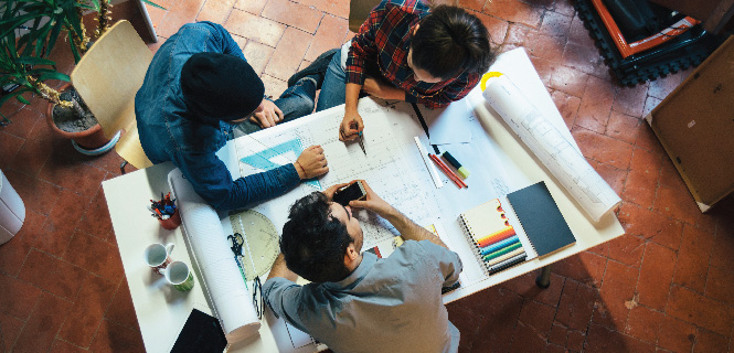 three co-workers sitting at a drafting table