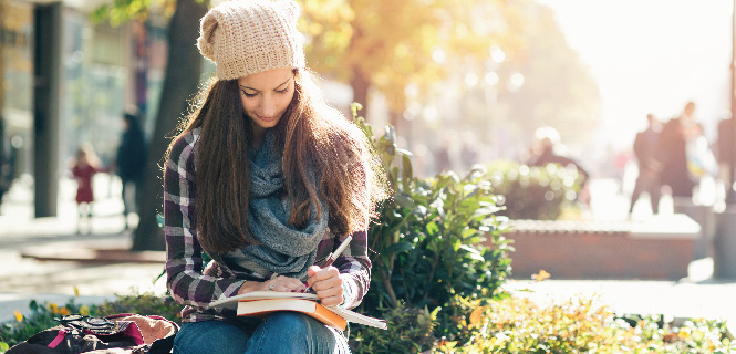 female student writing on a notebook